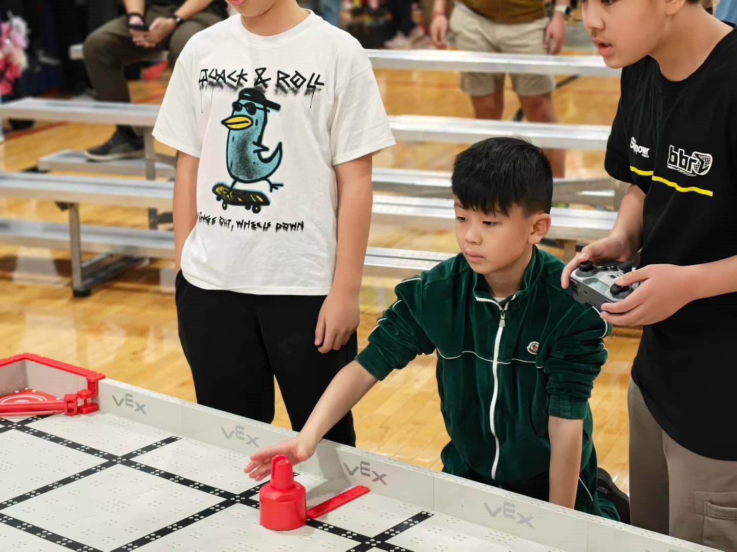 Students at the controls during a VEX IQ match, teammates watching