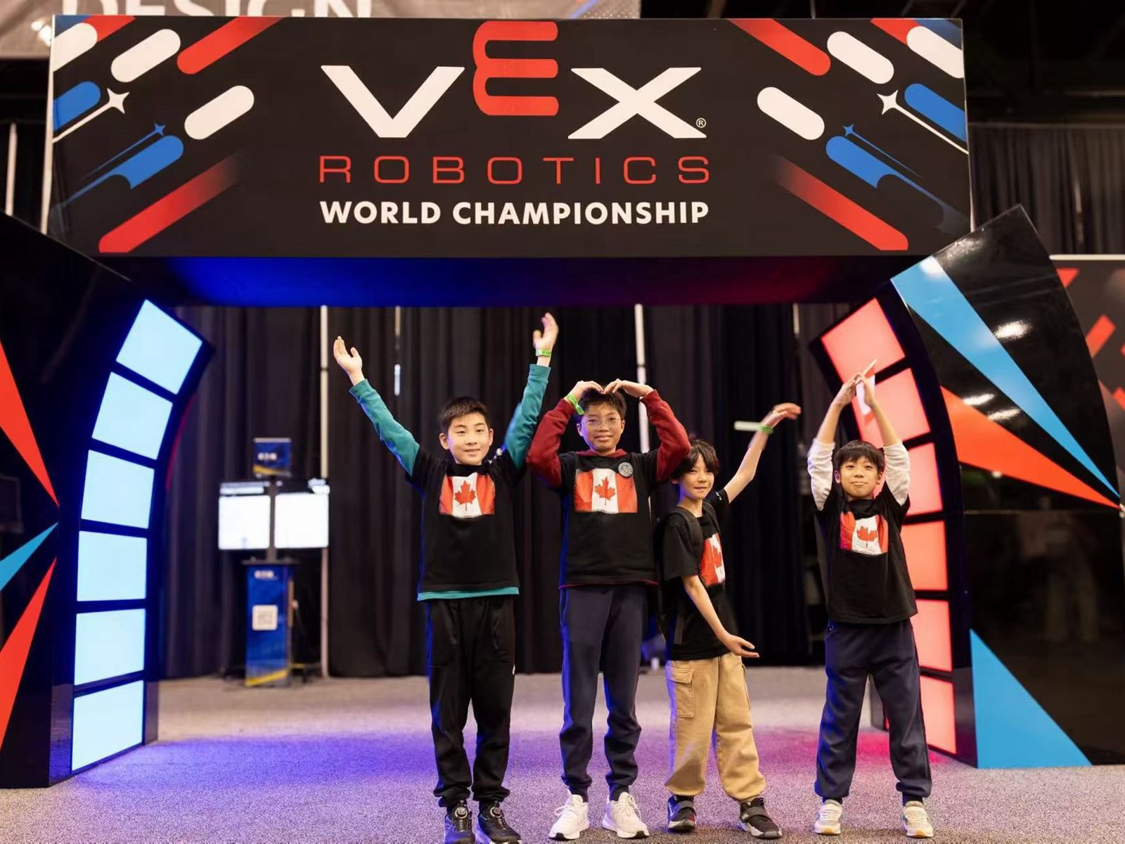 RoboPlanet students on stage at the VEX Robotics World Championship, arms raised