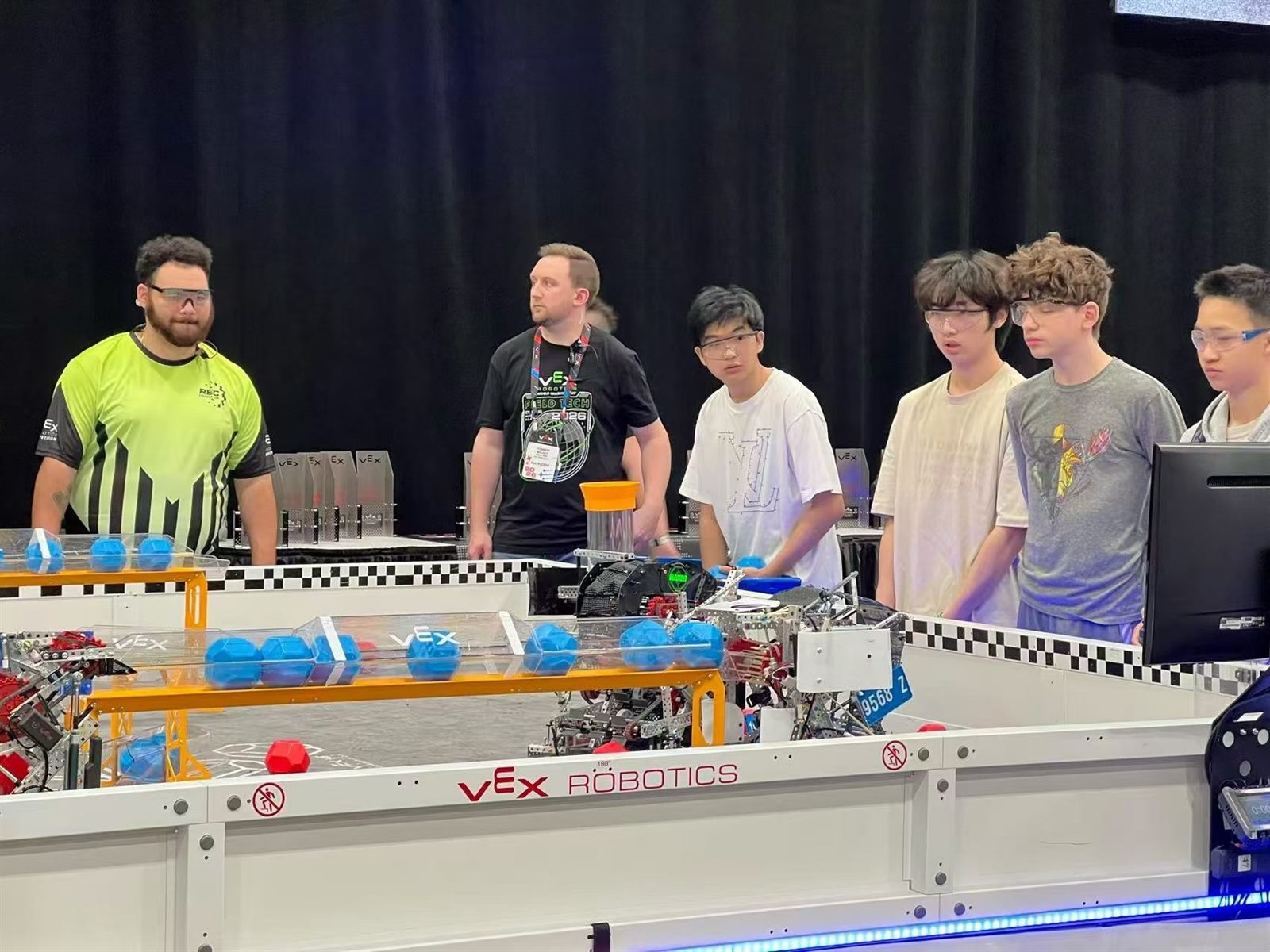 VEX V5 match underway on the competition field with referees watching